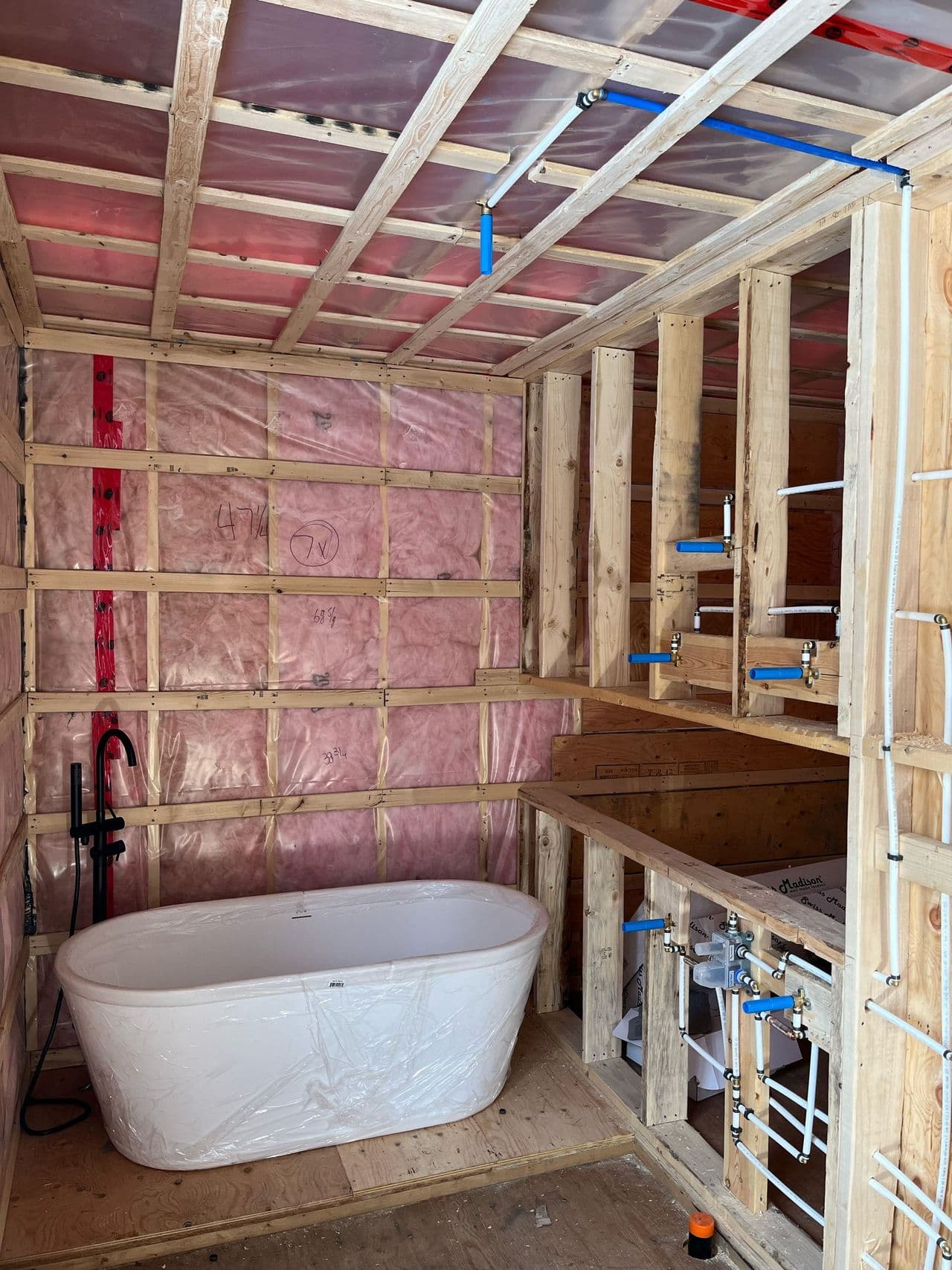 Salle de bain en chantier : bain autoportant, robinet sur pied et conduites PEX en attente pour la vanité et la douche